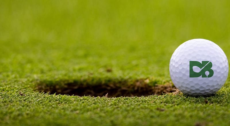 David Bailey Golfing Academy logo on the golf ball, golf ball is on the green grass near to the golf