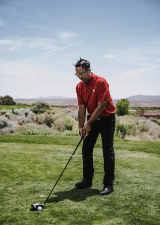 A male golfer with red shirt playing golf at green golf course